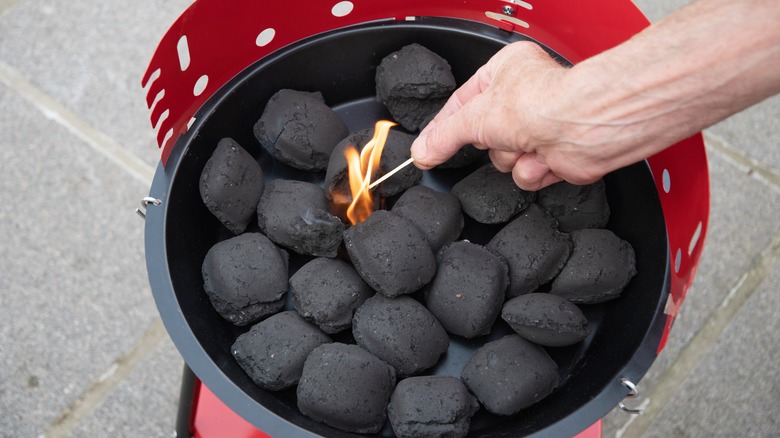 Person lighting charcoals with long match