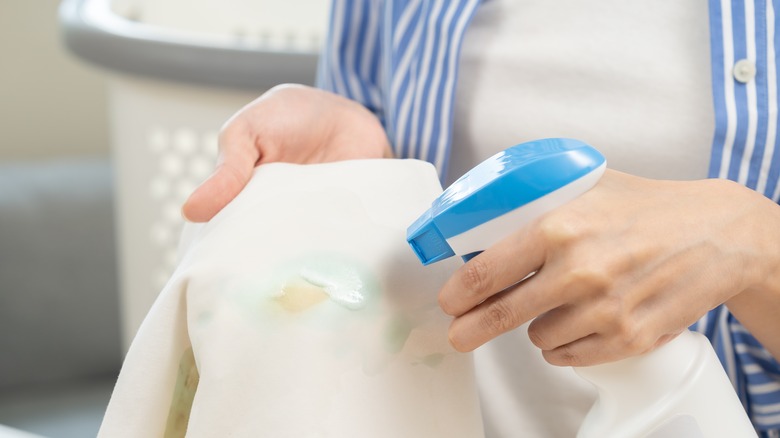 spraying stain remover on laundry