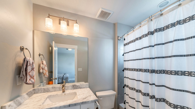 Bathroom with exhaust fan on ceiling by shower