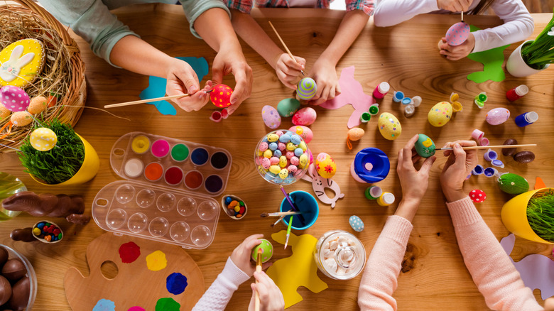 People around table painting eggs