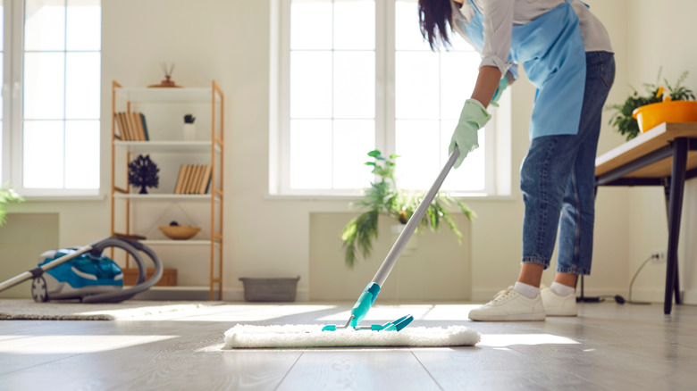 Woman cleaning laminate flooring with dust mop