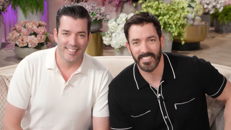 The Property Brothers smiling together on a couch