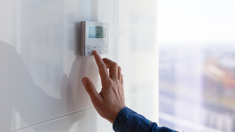 person adjusting temperature on wall