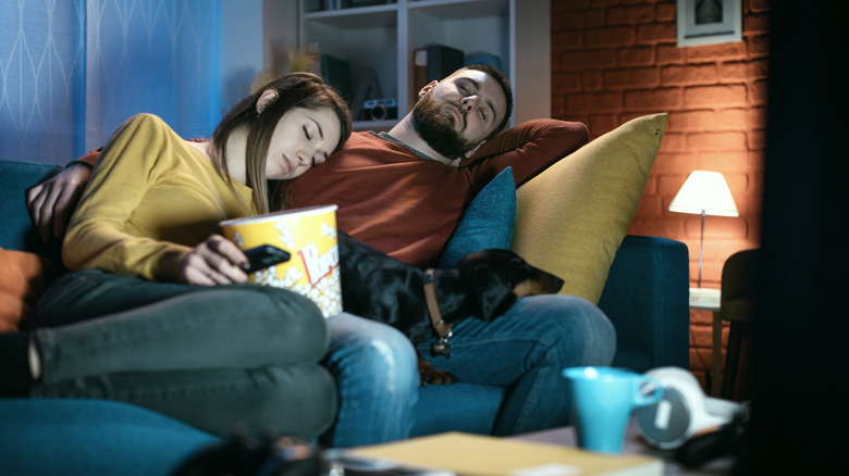 Couple asleep on couch with dog