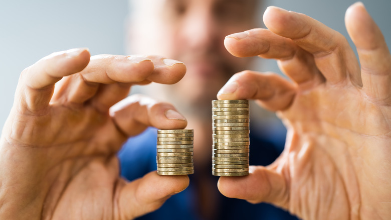 two hands holding coin stacks