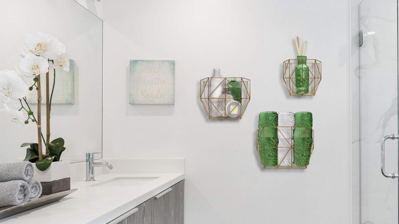 Three geometric wire baskets arranged on a bathroom wall with bathroom essentials stored inside