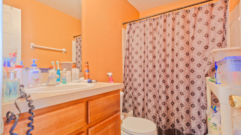 A bright orange bathroom with clutter on the counter