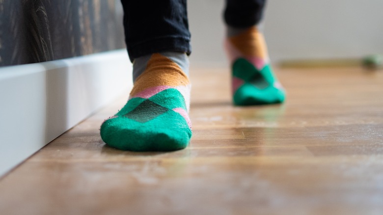 Person in green socks walking on hardwood floor