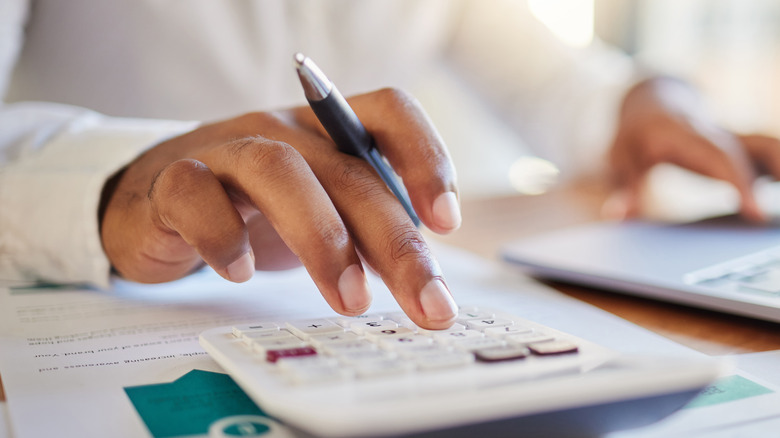 person using calculator and laptop