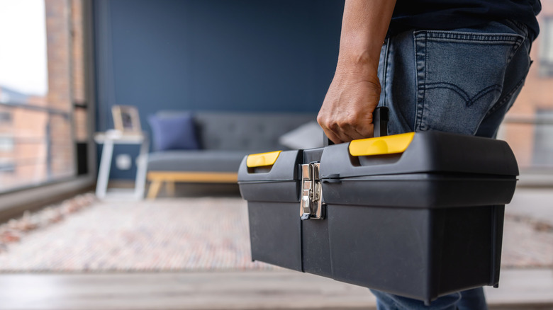 electrician carrying toolbox into home