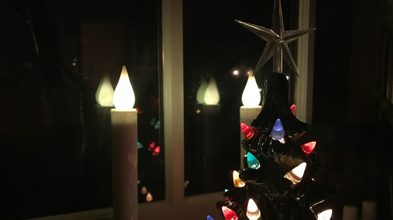 Vintage ceramic Christmas tree by a window with two electric candlesticks