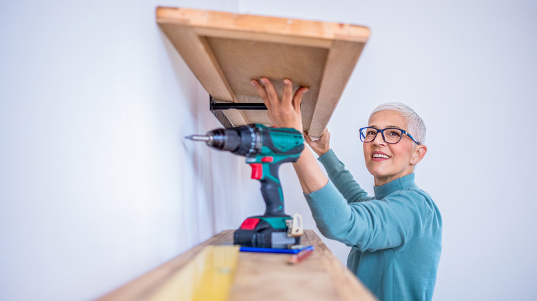 Person installing a floating shelf on the wall