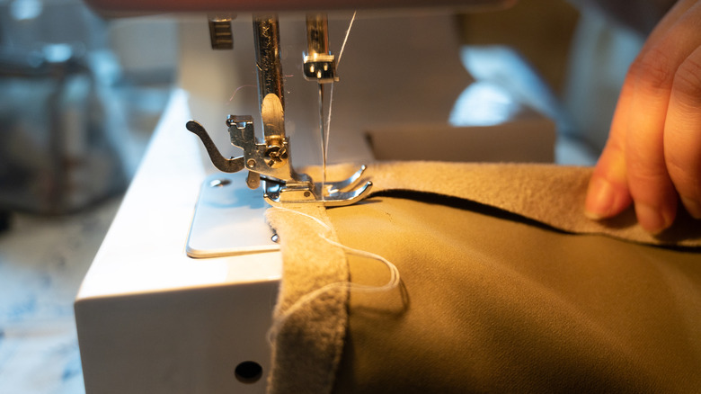 A person on a sewing machine creating a hem in fabric