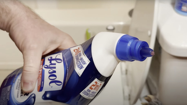 A person holding a bottle of Lysol toilet bowl cleaner