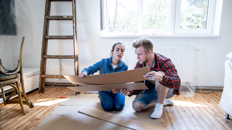 young couple laying flexible vinyl flooring