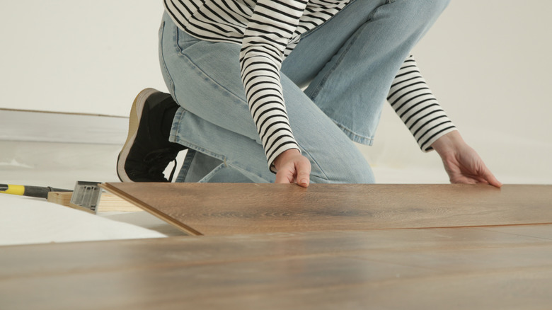 young woman laying mid-toned laminate floor panels