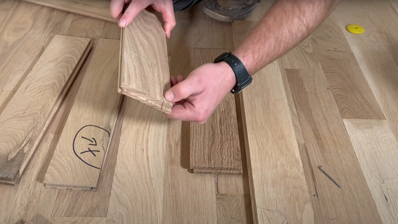 man examining medium hardwood planks for DIY install