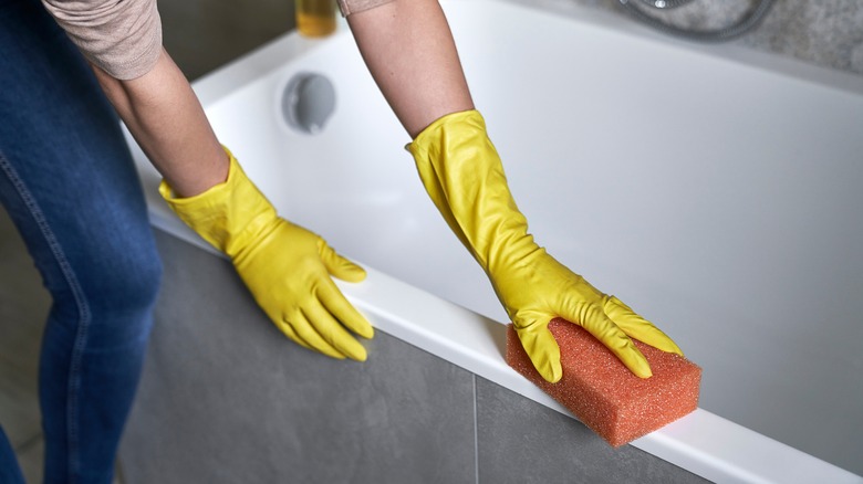 Using sponge to clean bathtub