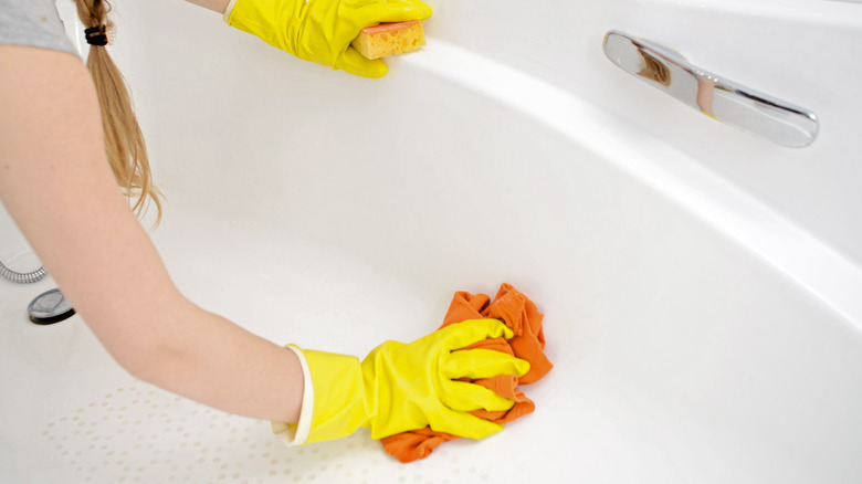 Woman scrubbing bath with cloth