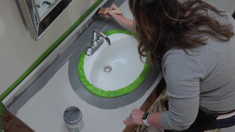 woman painting bathroom countertop