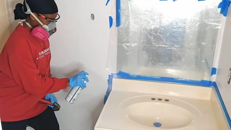 woman spray painting bathroom vanity