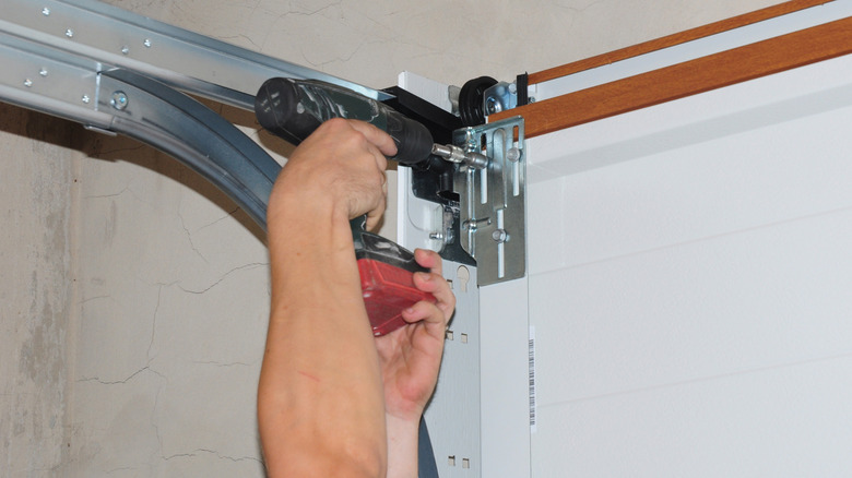 A man making adjustments to garage door fittings