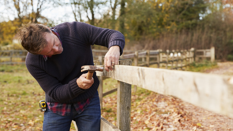 Man hammering a wood fence together in cold weather