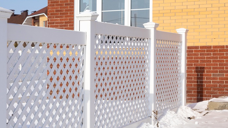 A white, open-style vinyl fence in a snowy yard