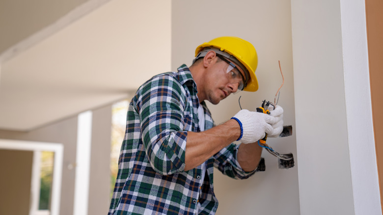 An electrician inspects wiring inside a home