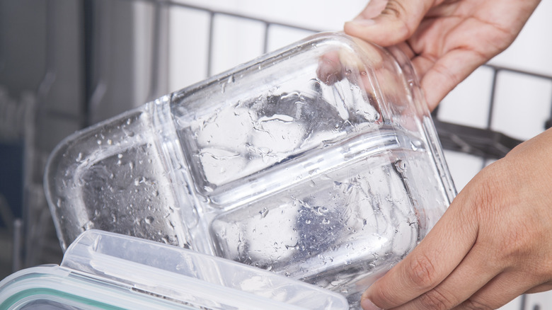 Hands placing glass containers in dishwasher