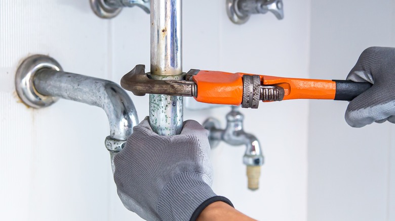 Person holding wrench on pipe