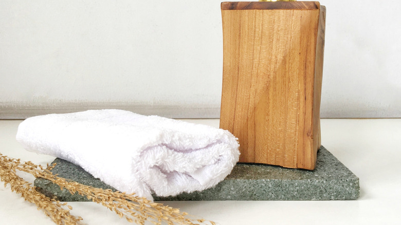 A towel and a wood soap dispenser on a stone slab