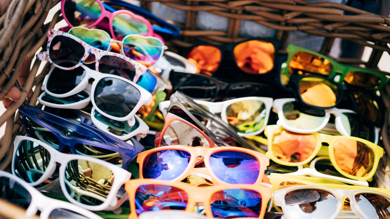 Various colorful sunglasses in a wicker basket