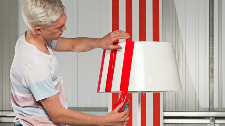 Person applying tape to lampshade