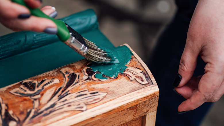 Person doing a dipped paint makeover on a worn wooden drawer