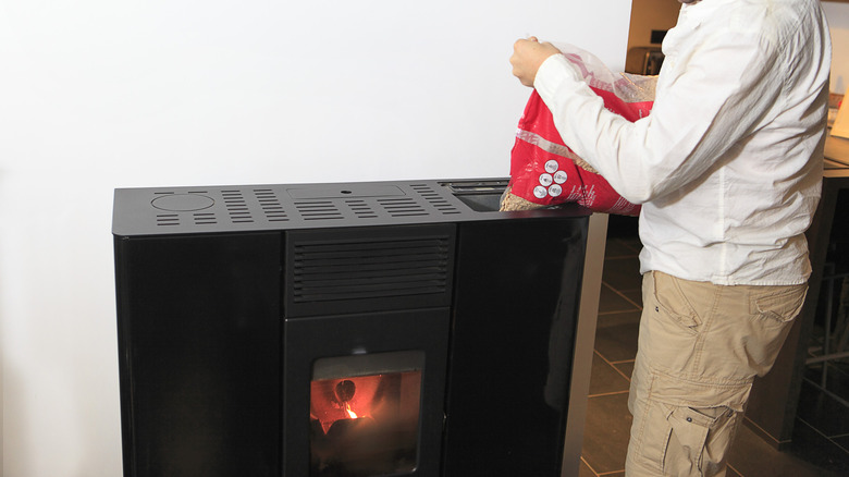 A person pouring wood pellets into a pellet stove