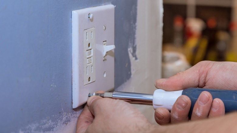 unscrewing outlet cover from wall