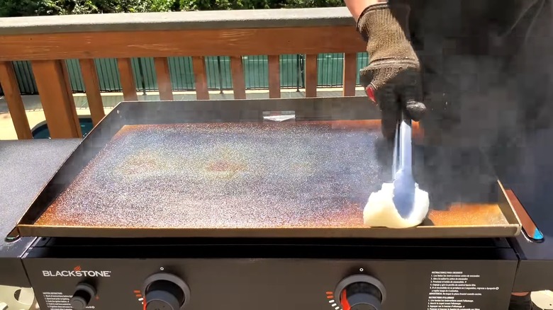 person coating oil on Blackstone griddle