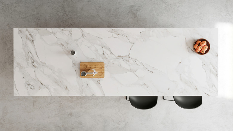 Top-down view of marble island with bar stools, coffee tray, and apples in a bowl