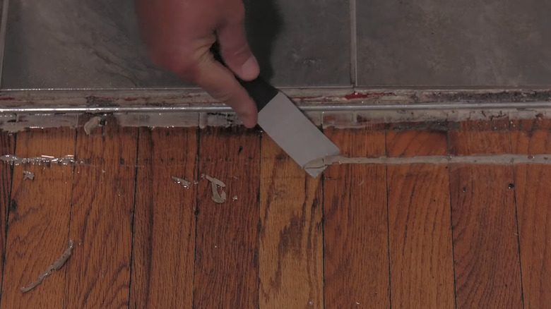 Hand scrapes stuck-on floor adhesive