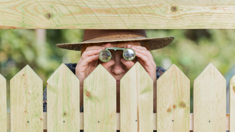 man using binoculars behind fence