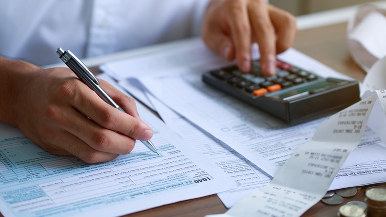 person with calculator working on taxes