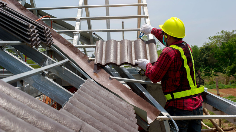 construction worker roofing with tiles