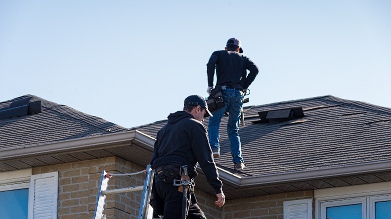 Men fixing damaged roof shingles 