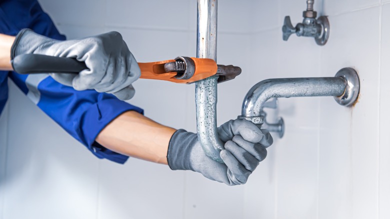 person fixing sink plumbing pipes