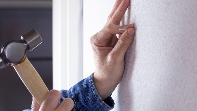 Woman putting nail holes in wall