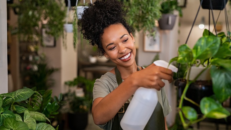 smiling woman spraying plants