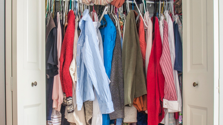 Clothes are piled up in a messy closet