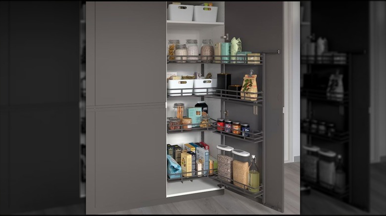 Tall gray cabinets open to reveal a pullout pantry system from IKEA packed with pantry food staples