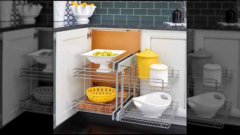 A corner cabinet is fitted with a blind shelving unit with yellow and white decorative pieces on it